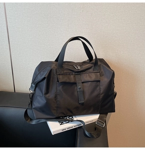 Close-up of black nylon travel bag with adjustable strap and buckle pocket detail