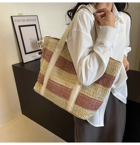 Detail of a large woven tote bag with beige and brick red stripes and fabric straps