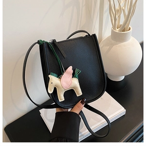 Detail of black lychee grain leather bucket bag with a colorful horse charm pendant