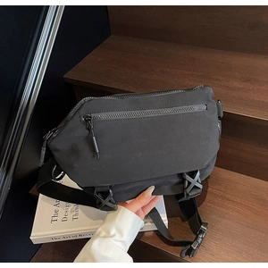 Detail einer schwarzen Nylon-Umhängetasche mit Schnalle und Reißverschlussfächern auf Holz