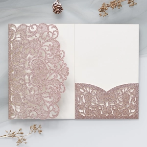Macro detail of rose gold laser-cut heart invitation with glitter finish and lace pattern