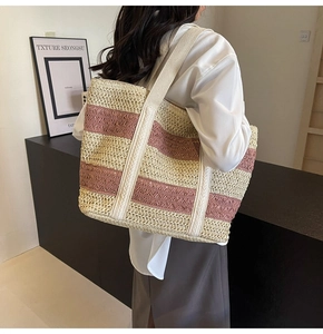 Model view of a large woven straw beach bag featuring pink and beige stripes