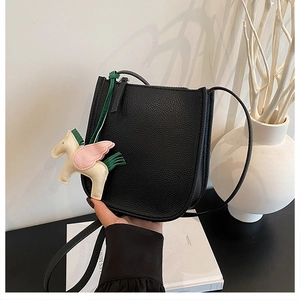 Detail of a black pebbled leather bucket bag featuring a horse charm and zipper closure