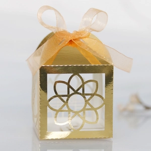 Detailed laser-cut gold gift box with intricate floral patterns and silk ribbon bow