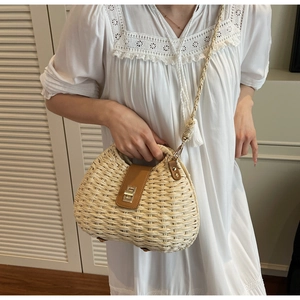 Close-up of woven straw handbag with brown leather flap and metallic twist lock