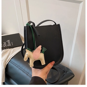 Detail of black lychee grain bucket bag with colorful leather pegasus charm accessory