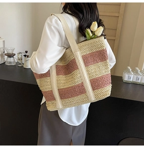 Detail view of large straw tote bag with pink stripes and thick woven shoulder straps