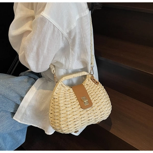 Detail of hand-woven straw crossbody bag with leather strap and metal twist lock