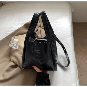 Close-up of black croc-embossed leather tote bag with dual handles and detachable shoulder strap