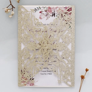Macro shot of gold glitter laser cut floral wedding invitation with watercolor flower detail