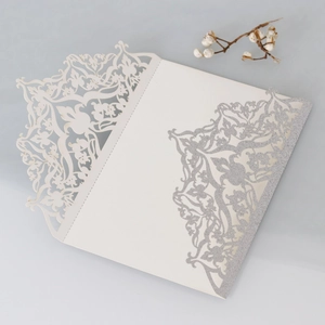 Close-up of laser cut wedding invitation cover with silver glitter floral pattern