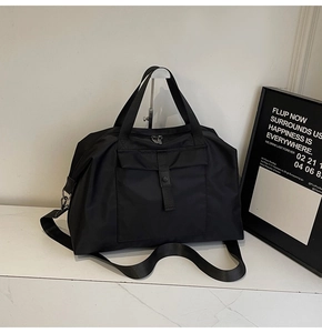 Detail of black nylon travel bag with durable handles and metal snap pocket design