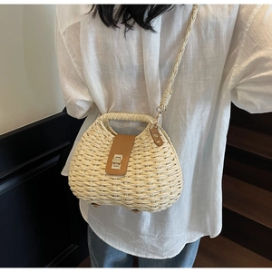 Detail of woven straw bag featuring brown leather flap and metallic twist lock closure