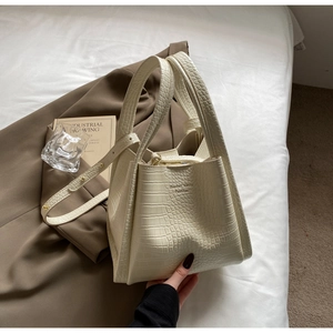 Detail of creamy white crocodile pattern texture on a minimalist stylish bucket bag