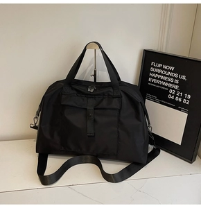Close-up of black nylon travel bag with adjustable shoulder strap and buckle pocket