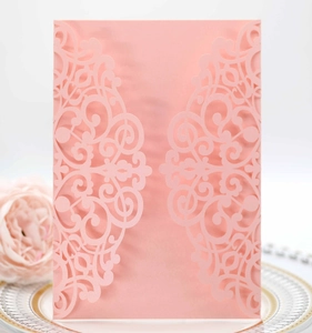 Detail of laser-cut pink wedding invitation with elegant vine patterns and a matte finish