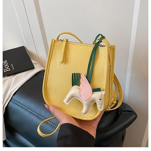 Detail of a lemon yellow lychee texture leather bucket bag with a cute horse charm