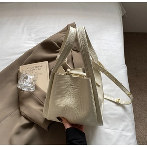 Detail of cream faux crocodile embossed handbag with double handles and logo branding