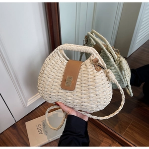 Detail of hand-woven straw bag featuring brown leather flap and golden twist lock