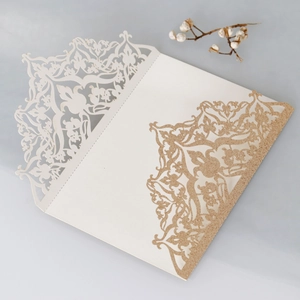 Detail of laser-cut wedding invitation with hollow floral pattern and gold glitter