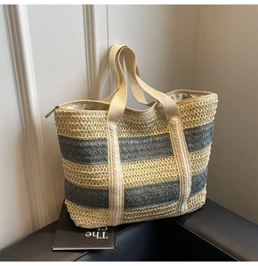 Close-up of color-block straw tote bag with striped weave pattern and reinforced handles