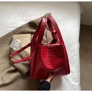 Close-up of red crocodile pattern leather tote bag with metallic logo and adjustable strap