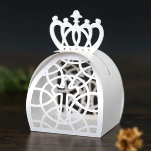 Close-up of laser-cut white wedding favor box with cross pattern and crown shape