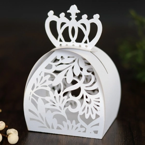 Gros plan de la boîte à bonbons blanche découpée au laser avec couronne et fleurs
