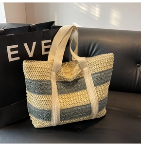 Detail of contrast color straw tote bag with blue and beige stripes and woven handle
