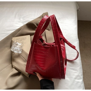 Detail of red crocodile pattern tote bag with wide handles on a khaki blazer