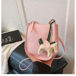 Close-up of pink lychee grain leather bucket bag with decorative pegasus charm accessory