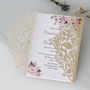 Detailed close-up of laser-cut wedding invitation with glitter and floral inner card