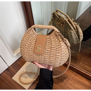 Detail of handwoven straw bag featuring a leather strap, gold clasp, and mirror reflection