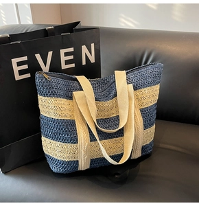 Detail of blue and white striped straw beach bag featuring wide woven shoulder straps