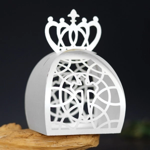 Macro detail of laser-cut crown gift box in pearlescent white paper on wooden base