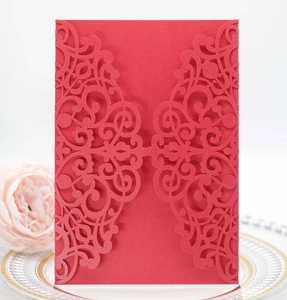 Detail of red laser-cut invitation cover with baroque floral patterns on decorative plate