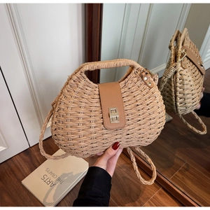 Close-up of hand-woven straw bag with premium brown leather flap and golden metal clasp