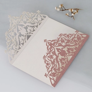 Detail of laser-cut ivory wedding invitation with rose gold glitter and floral hollow patterns