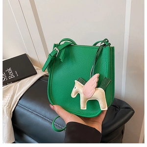 Close-up of green lychee leather bucket bag with a flying horse charm and zipper