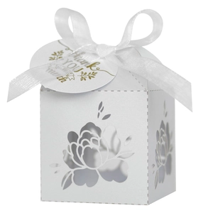 Detail of laser-cut floral pattern on white wedding favor box with silk ribbon bow