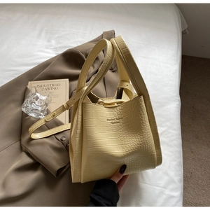 Detail of creamy yellow tote bag with crocodile texture and thin shoulder strap