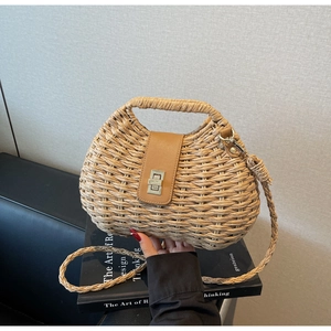 Detail of woven straw handbag featuring a brown leather flap and silver metal twist lock