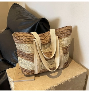 Detailed close-up of woven straw tote texture with contrast stripes and top zipper