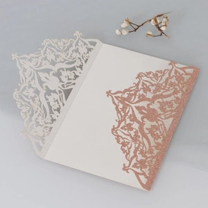 Detail of laser-cut ivory card with intricate floral patterns and rose gold glitter accents