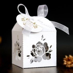 Detail of laser-cut white wedding favor box with Thank You tag and white ribbon