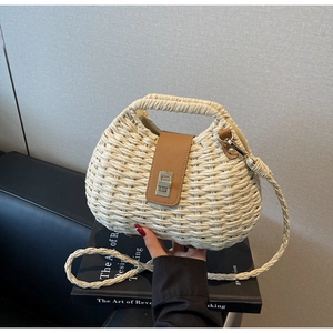 Detail of woven straw handbag featuring brown leather flap and metallic turn-lock closure