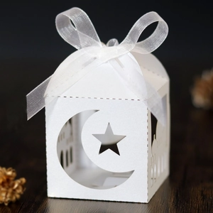 Detail showing white laser-cut Ramadan gift box with moon, star patterns and ribbon