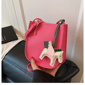 Detail of pink lychee leather bag featuring a Pegasus charm and adjustable shoulder strap