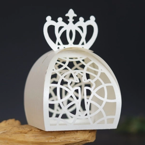 Macro shot of white laser-cut crown gift box with intricate hollow design on dark wood