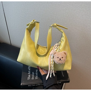 Detail of lime green hobo bag featuring smooth leather and plush bear charm